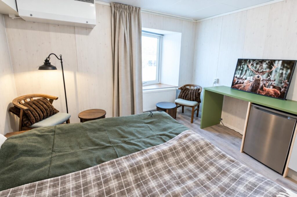 Tvåbäddsrum med grön ullfilt och rutig pläd